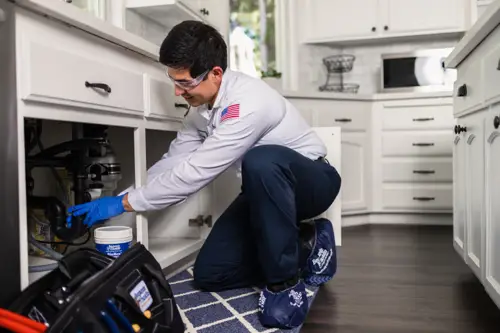 Diego, a Benjamin Franklin Plumbing Tech working on pipes under a sink